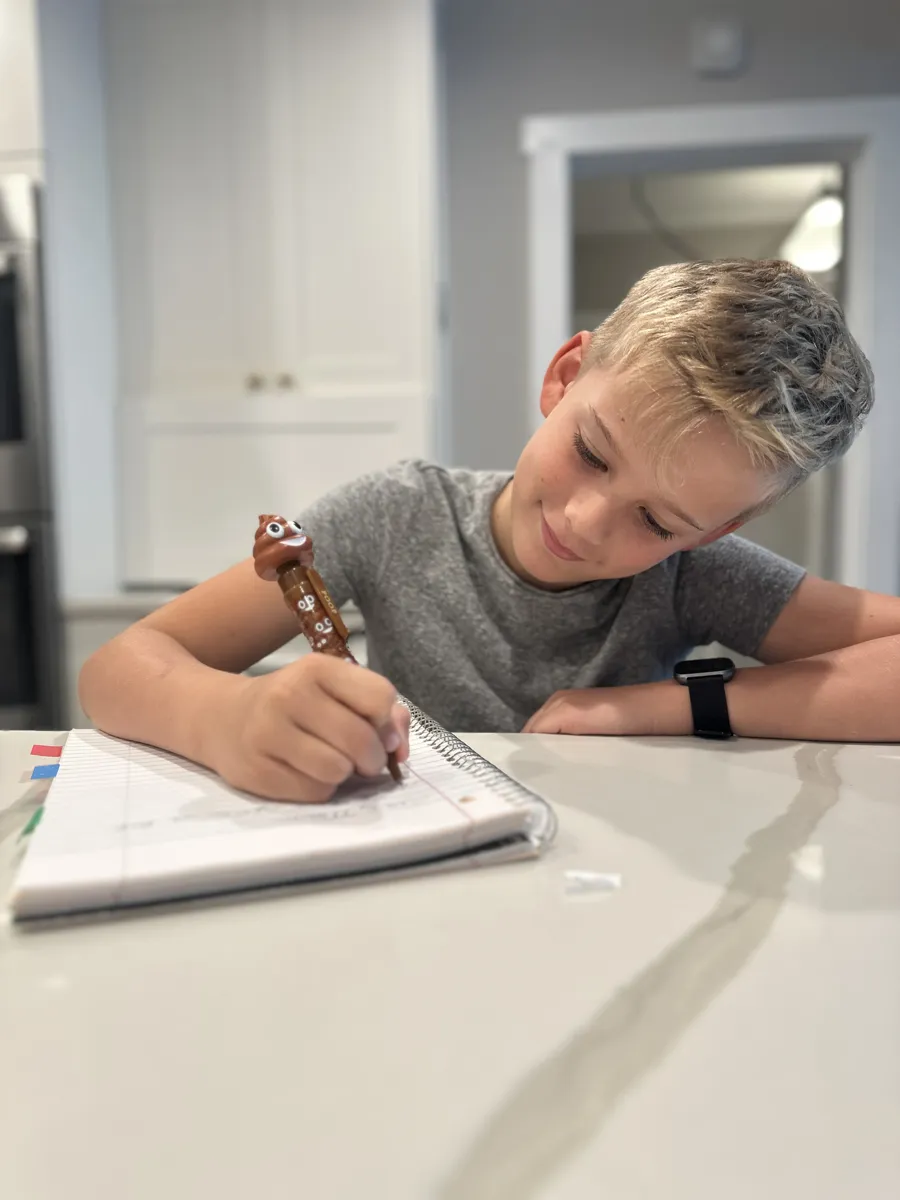 A kid writing with the Poop Pen